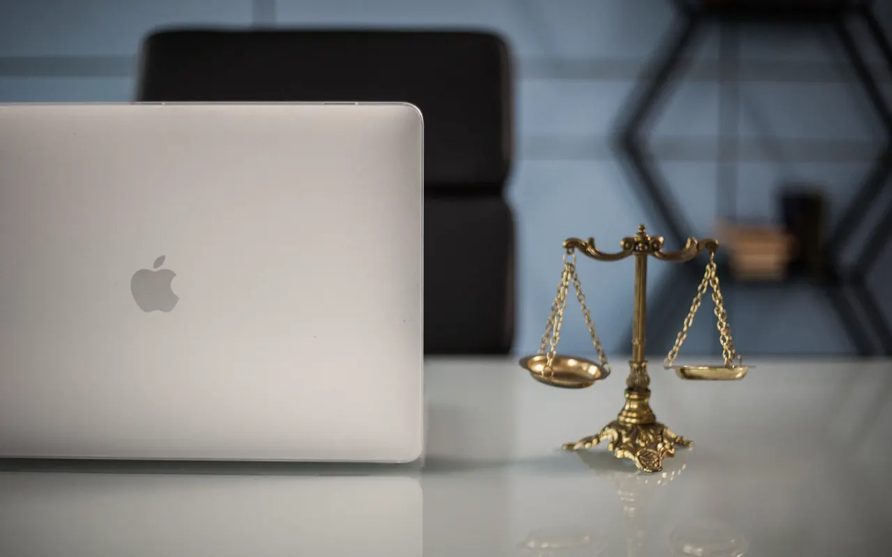 Golden balance scale next to a laptop on an office desk