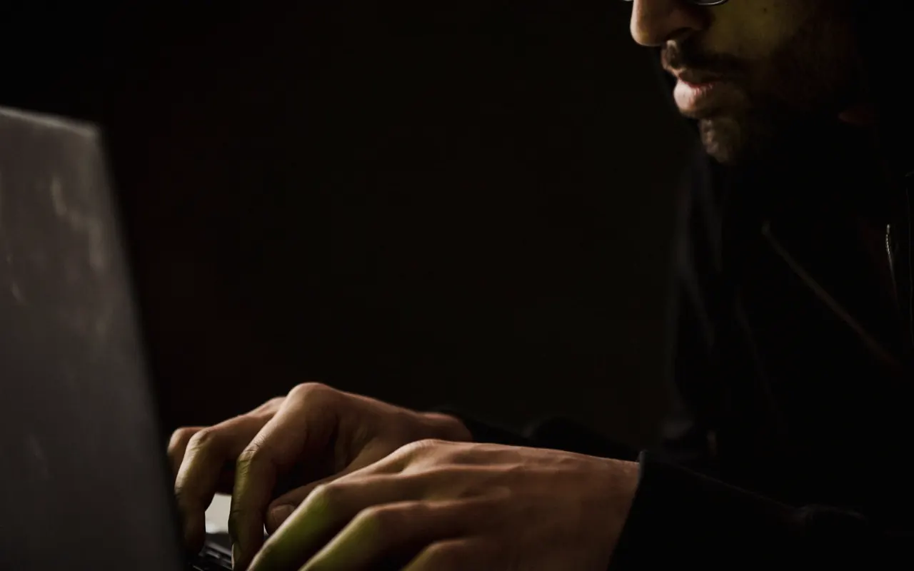 Person watching a video on a laptop at a desk at night